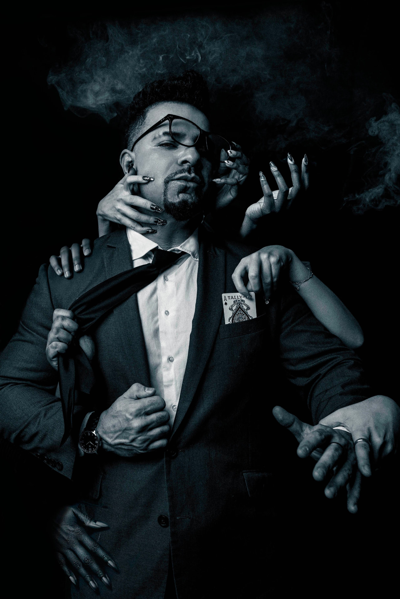 Emran Riaz, NYC mentalist and magician, in a dark suit surrounded by reaching hands